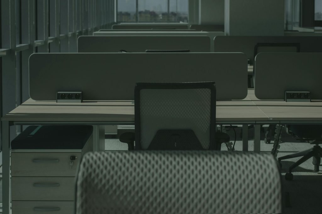 A sleek modern office with multiple desks and chairs, showcasing an empty and orderly workspace.